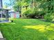 View of backyard featuring lush green grass, a storage shed, and mature landscaping providing privacy at 1475 Woodington Cir, Lawrenceville, GA 30044