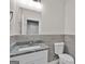 Well-lit bathroom featuring a modern vanity with a granite countertop, complemented by gray tiled walls and a sleek toilet at 250 Stonecreek Pkwy, Covington, GA 30016
