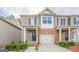 Inviting townhome featuring a garage, brick detailing, and lush, green landscaping at 2705 Maple Park Pl # 29, Cumming, GA 30041