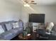 Cozy living room with plush gray sofa, decorative pillows, and a modern ceiling fan at 579 Wexwood Dr, Riverdale, GA 30274