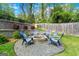 Outdoor stone fire pit surrounded by chairs in a landscaped backyard with a wood fence and greenery at 2940 Parkridge Ne Dr, Brookhaven, GA 30319