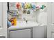 Bright laundry room with a deluxe service sign, shelving and white washer and dryer at 2014 Big Cypress Ln, Locust Grove, GA 30248