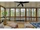 Bright screened-in porch with expansive window views and a ceiling fan, blending indoor comfort with outdoor scenery at 3230 Riverhill Ct, Cumming, GA 30041