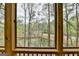 Framed view through screened-in porch showcasing a tranquil pond surrounded by lush trees and foliage at 3230 Riverhill Ct, Cumming, GA 30041