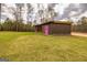 A well-kept brown barn on a green lawn, accented by a vibrant pink door, adds rustic charm at 168 Lakeview Dr, Grantville, GA 30220