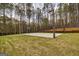 A backyard basketball court with bleachers is surrounded by a dark wooden fence and a natural wooded area at 168 Lakeview Dr, Grantville, GA 30220