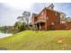 Back of a brick home featuring a wooden deck, steps, and a lake view from the lawn at 170 Austin Oaks Dr, Ellenwood, GA 30294