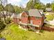 Back view of a red brick home with a wooden deck, lush green lawn and mature trees at 170 Austin Oaks Dr, Ellenwood, GA 30294
