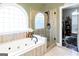 Bright bathroom with a jacuzzi tub, walk-in shower, travertine tile and a view into a large closet at 101 Westminster Way, Mcdonough, GA 30253