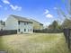 View of the backyard featuring a black fence surrounding the green lawn and back exterior of the house at 789 Galveston Way, Mcdonough, GA 30253