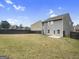 Spacious backyard featuring a green lawn, black fence, and gray two-story home exterior, ideal for outdoor enjoyment at 789 Galveston Way, Mcdonough, GA 30253