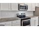 Close-up of the kitchen featuring stainless steel appliances, granite countertops, and white cabinets at 789 Galveston Way, Mcdonough, GA 30253