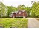 Brick home surrounded by a grassy lawn and mature trees, featuring dark shutters and an attached garage at 1015 Middlebrook Dr, Mcdonough, GA 30252