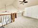 Open second floor loft area with neutral carpeting, wood railings, and vaulted ceilings with fans at 645 Crossbridge Aly, Johns Creek, GA 30022