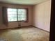 Pink bedroom with a window, carpet, and visible wall damage at 8395 Rivertown Rd, Fairburn, GA 30213