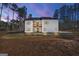 Exterior rear elevation of white farmhouse with black trim windows with pink and purple sky at dusk at 140 Wesley Pl, Fayetteville, GA 30214
