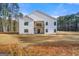 Back exterior featuring white siding, a small second story balcony, and a well-manicured lawn with surrounding trees at 130 Wesley Pl, Fayetteville, GA 30214