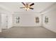 Spacious bedroom with neutral carpet, a ceiling fan, tray ceiling, and natural light from three windows at 4090 Spencer Ln, Stonecrest, GA 30038