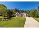 Traditional single-Gathering home with a landscaped front yard, mature trees, and a curved driveway at 230 Hidden Brook Trl, Fayetteville, GA 30215