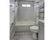 Bright bathroom featuring a shower-tub combo, tile walls and floors, toilet, and chrome shelving at 9689 Pintail Trl, Jonesboro, GA 30238