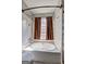 A relaxing white soaking tub situated beneath a window with framed brown curtains at 9689 Pintail Trl, Jonesboro, GA 30238