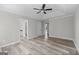 Bedroom featuring tray ceiling, ceiling fan, views to the en suite, and wood-look floors at 3540 Owl Brow Ct, Cumming, GA 30028
