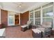 Relaxing covered back porch with brick flooring, ceiling fan, and comfortable seating; kitchen viewable through french doors at 1570 Woodberry Run Dr, Snellville, GA 30078