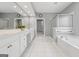 Well-lit bathroom with double sinks, bathtub, shower with glass door, and tiled flooring at 1570 Woodberry Run Dr, Snellville, GA 30078