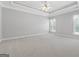 A sizable bedroom with neutral carpet, white trim, large windows with curtains, and ceiling fan at 1570 Woodberry Run Dr, Snellville, GA 30078