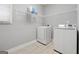 Functional laundry room with a washer, dryer, wire shelving, and neutral tiled flooring at 1570 Woodberry Run Dr, Snellville, GA 30078