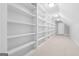 Spacious walk-in closet with ample storage featuring rows of shelving and neutral carpet flooring at 1570 Woodberry Run Dr, Snellville, GA 30078