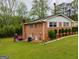 Rear view of brick home with lush lawn and stairway to elevated deck at 6501 River Run Rd, Riverdale, GA 30274
