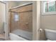 Clean bathroom with a shower-tub with glass door and beige tile, and nearby toilet at 5297 Heron Bay Blvd, Locust Grove, GA 30248
