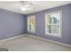 Cozy bedroom with plush carpet, neutral color palette, ceiling fan, and bright, double-hung windows at 5297 Heron Bay Blvd, Locust Grove, GA 30248