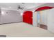 Expansive bonus room with neutral carpet, ceiling fan, and bold red accent wall at 5297 Heron Bay Blvd, Locust Grove, GA 30248