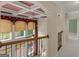 Bright hallway features detailed coffered ceiling, large windows, and wrought iron railing, adding architectural charm at 5297 Heron Bay Blvd, Locust Grove, GA 30248