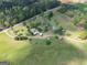 Overhead aerial image of property showcasing house, barns, outbuildings, open field, and wooded space at 3011 Broughton Rd, Newborn, GA 30056