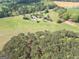 Expansive aerial view of the property showcasing the home, outbuildings, and surrounding wooded acreage and fields at 3011 Broughton Rd, Newborn, GA 30056