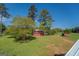 Spacious grounds feature a bright red barn surrounded by lush green trees and a bright blue sky at 3011 Broughton Rd, Newborn, GA 30056