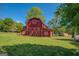 Exterior view of a charming red barn with white trim accents and a spacious yard, perfect for rural living at 3011 Broughton Rd, Newborn, GA 30056