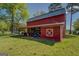 Exterior view of a well-maintained red barn featuring white trim accents against the clear blue sky and green land at 3011 Broughton Rd, Newborn, GA 30056