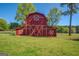 Exterior view of a well-maintained red barn featuring white trim accents against the clear blue sky and green land at 3011 Broughton Rd, Newborn, GA 30056
