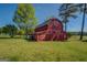 Exterior view of a red barn showcasing its covered area, green grass, and a sturdy structure with white trim accents at 3011 Broughton Rd, Newborn, GA 30056