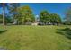 Expansive grassy field with trees leads to a cozy-looking home featuring a white porch and welcoming stairs at 3011 Broughton Rd, Newborn, GA 30056