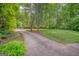 View of a long driveway leading to a brick home surrounded by lush landscaping at 205 Olde Oak Dr, Jonesboro, GA 30238