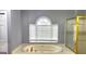 Bathroom features a soaking tub underneath a window, a glass shower, and neutral tile flooring at 1622 Brentwood Se Xing, Conyers, GA 30013
