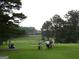 Scenic view of golfers on the lush green golf course with mature trees and a clubhouse in the background at 107 Rolling Grn, Peachtree City, GA 30269
