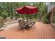 Outdoor patio featuring a dining set with a red umbrella surrounded by lush landscaping at 107 Rolling Grn, Peachtree City, GA 30269