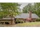 Wide shot of a house exterior showcasing a well-manicured lawn, brick chimney, and wooden deck at 107 Rolling Grn, Peachtree City, GA 30269