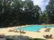 Outdoor pool with lounge chairs and umbrellas surrounded by lush greenery at 107 Rolling Grn, Peachtree City, GA 30269